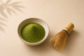 Existence Brewed Focus ceremonial matcha powder in a bowl beside a bamboo whisk.